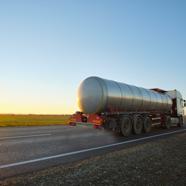 Petrol cargo truck driving on highway hauling oil products. Delivery transportation and logistics concept.